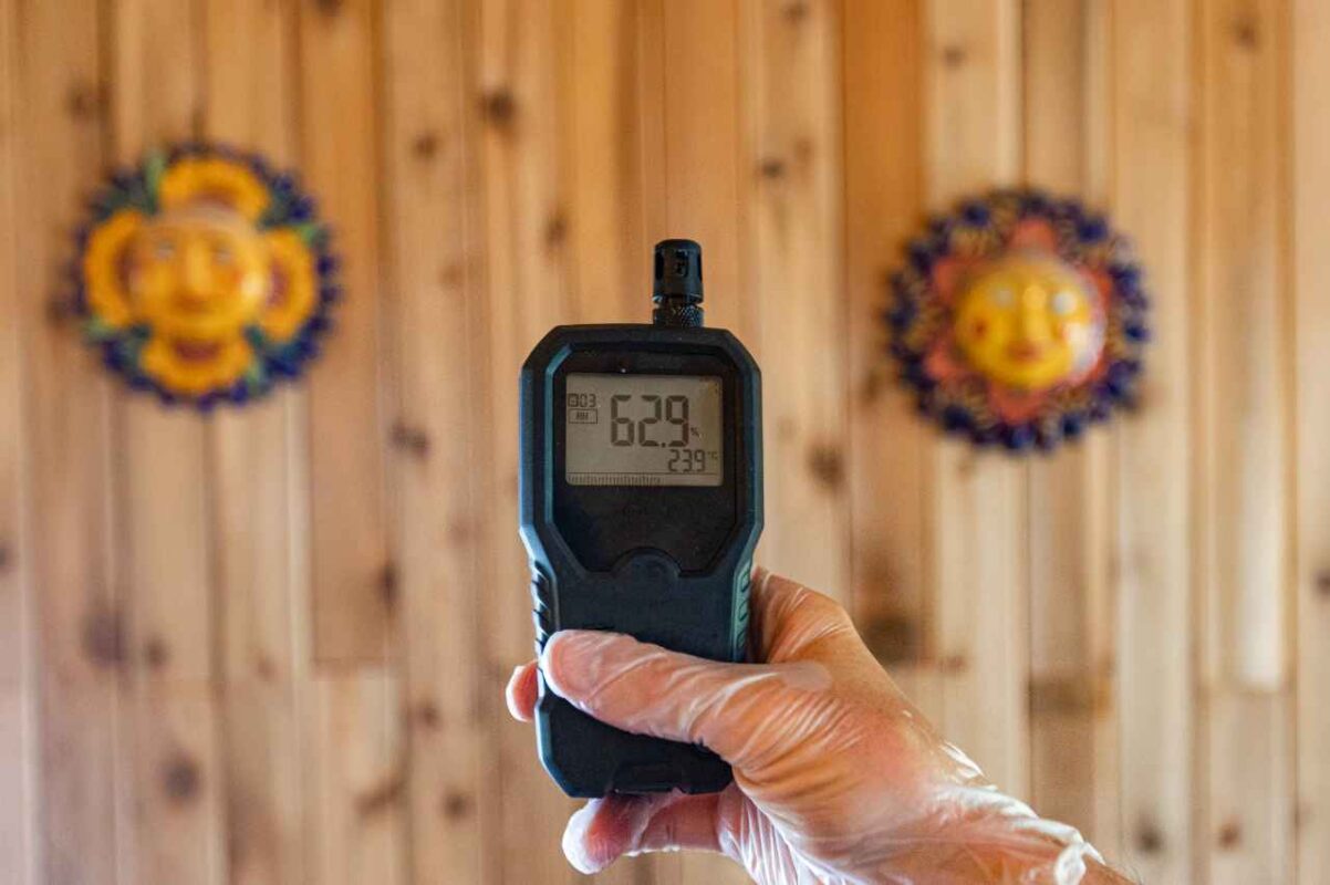 a hand holding a device with a temperature to do Indoor Air Quality Assessment